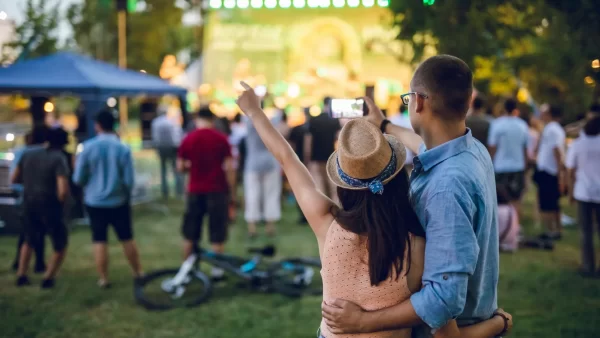 Couple side-hugging and dancing at an outdoor concert in a park